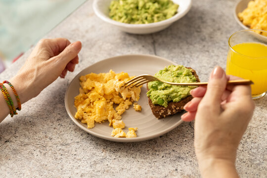 Eating Healthy Breakfast of Scrambled Eggs and Avocado Toast