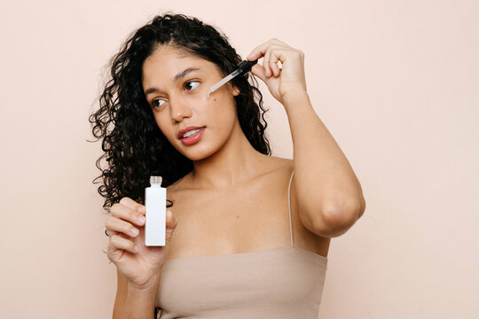 Woman applying serum on her face 