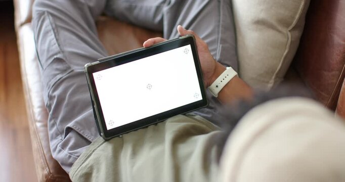 Man is reclining on sofa, tablet resting on lap while adjusting tilt to align markers