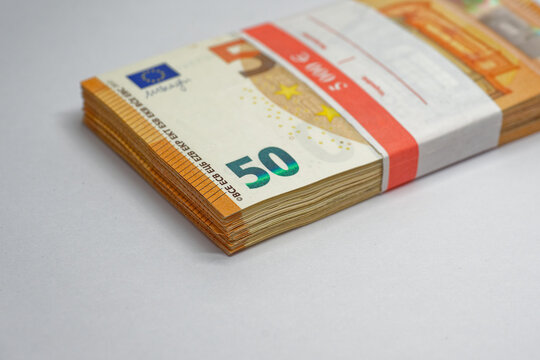 Stack of fifty euro banknotes 5000 Euro bundled with a red paper band on white surface