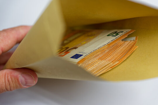 Hand holding kraft envelope filled with aligned fifty euro notes