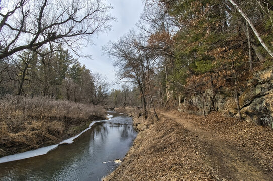 View of The Ice Cave Trail passing between a small stream and sandstone cliffs on a winter day at Wildcat Mountain State Park near Ontario, Wisconsin.