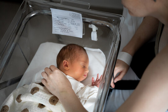 Mother caring for newborn baby in hospital bassinet