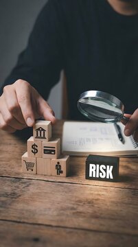 Financial risk management concept with wooden blocks showing banking and business icons and magnifying glass highlighting risk analysis
