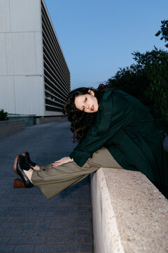Woman posing on a concrete ledge at dusk