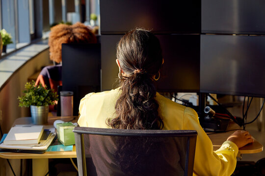 Professional working at multi-monitor workstation in office