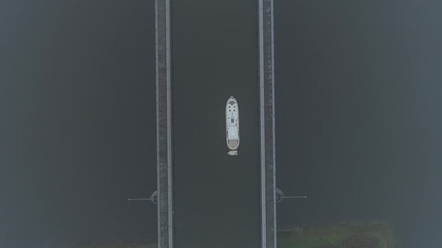 Zenithal forward drone movement above a boat navigating Magdeburg Water Bridge, emphasizing the symmetry of the elevated canal and structural geometry.