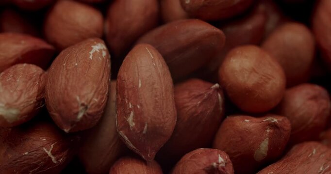 Closeup of a full wooden bowl of raw peanuts with skins rotating in slow motion, Top-down view of unpeeled raw peanuts in a wooden bowl slowly rotating on a clean white background