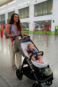 Mother pushing baby stroller in airport terminal