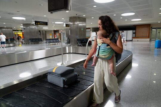 Mother with infant collecting luggage at baggage claim