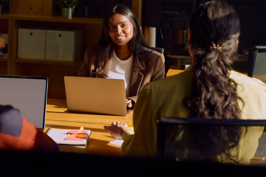 Business meeting with coworkers collaborating around laptops