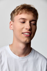 Naklejka premium Smile, youth, young man in casual wear with white tee under soft lighting, relaxed pose and gentle expression offering approachable lifestyle and fashion stock imagery for marketing use