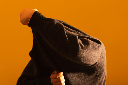 Model Taking Off a Navy Knit in Warm Backlight