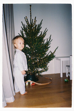 Toddler standing near a Christmas tree at home on analog film