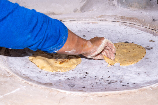 Hand making fresh corn tortillas on traditional comal