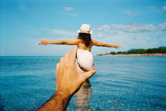 POV photo with a seashell covering the body of a woman at the beach