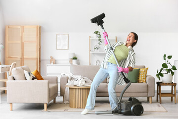Young woman with vacuum cleaner singing at home