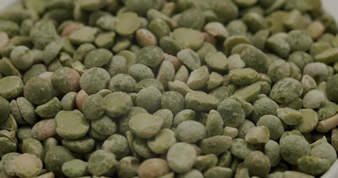 Raw green split peas rotating in a bowl in a detailed close-up shot, showcasing the texture and color of the healthy, nutritious, and protein-rich vegetarian food ingredient
