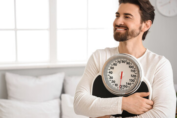 Young man with weight scales in bedroom