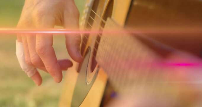 Guitarist with taped thumb picking and fretting, causing moving tabs over pink flare for music demo