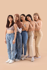 Fototapeta premium Group of young women hugging on beige background