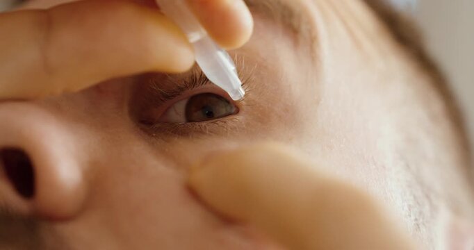 Extreme close-up of a man applying eye drops into his eye. Concept of eye care, dry eyes, medical treatment, hygiene and healthcare routine.