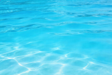 Clear turquoise water surface with gentle ripples, showcasing light refraction and tranquil aquatic texture. Ideal for representing summer, relaxation, and natural refreshment themes.