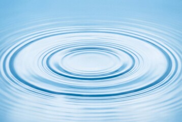Concentric ripples on clear blue water surface creating a serene abstract pattern