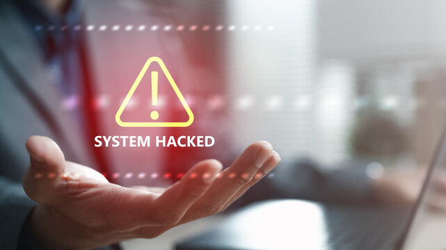 Business professional holding digital warning alert with system hacked message, representing cybersecurity breach, data protection risk, cyber attack threats, and enterprise network security failure.