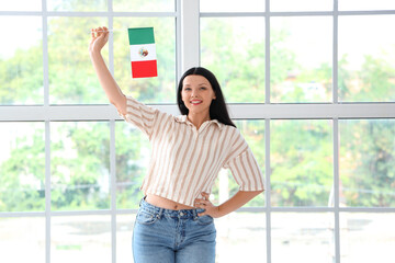 Young woman with Mexican flag near window at home