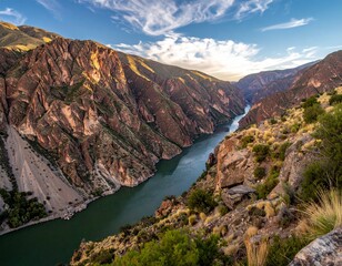 Fototapeta premium Majestic Canyon Landscape - A River Carving Through Towering Rock Formations Under a Cloudy Sky.
