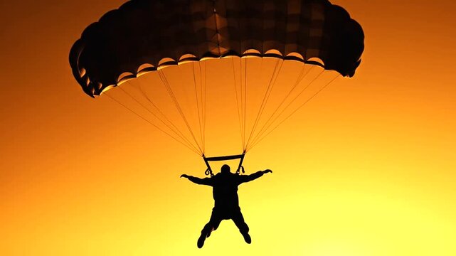 Parachutist Silhouettes Against Vibrant Sunset Sky.