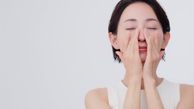 スキンケアプロセス／彼女は目を閉じ頬に手をあてている