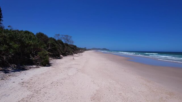 Sandy Tallow Beach With Coastal Shrubs And Trees In Byron Bay, NSW, Australia. wide drone shot