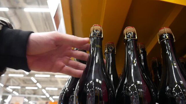 A cusomer's hand taking a bottle of wine from a display case