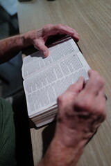 Naklejka premium elderly hands hold open a Christian bible while reading verses