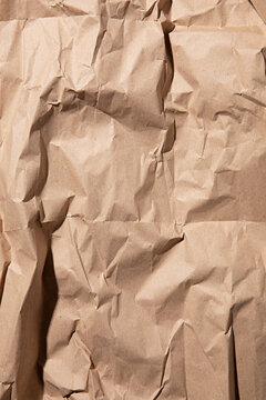 Close-up texture of crumpled brown kraft paper with dramatic shadows and highlights