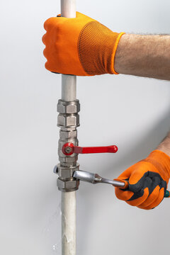 Technician plumber fixing leaking pipe of water.
