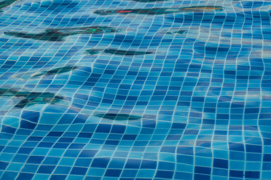Close up of blue mosaic tiles under clear rippling swimming pool water