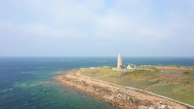 Aerial view of the Phare du Cap Levi lighthouse on the rugged coastline of Normandy, France, surrounded by clear blue sea and wild landscape.