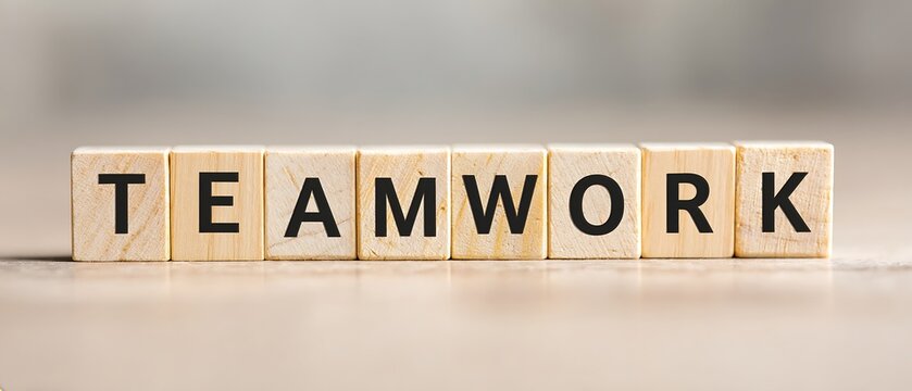 Wooden blocks spelling TEAMWORK on a light surface.