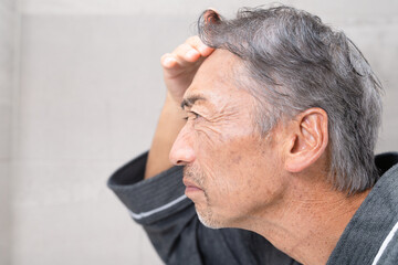 Obraz premium ヘアケアをするシニア男性 ビューティーイメージ