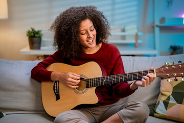 Latina beautiful woman playing guitar in living room at home. 