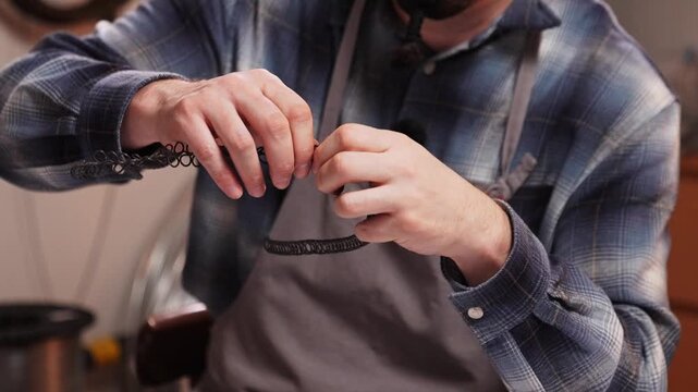 Medium close up of craftsman shaping decorative metal wire by hand in workshop. Traditional Slovak wire craft technique, drotarstvo folk art and handmade craftsmanship.