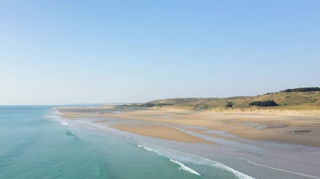 Aerial view of the expansive sandy shoreline and gentle waves at Plage de la Vieille eglise under a clear blue sky.