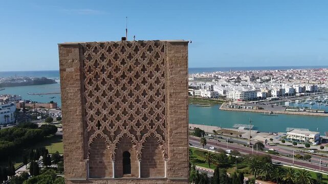 Exquisite drone close-up of the intricate stone patterns on Hassan Tower. Features a stunning backdrop of the Bou Regreg river, Marina Sal&eacute;, and the Atlantic coastline of Rabat city.