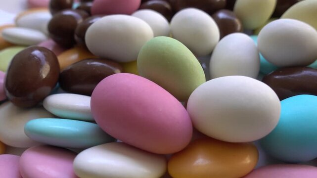 Pile of chocolate-covered almonds or colored pine nut almonds. Easter season.