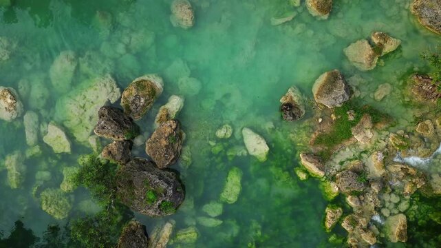 Slow upward shot of Bolinao Falls 3 cascading waterfall flowing into a cool turquoise pool framed by limestone rock and tropical foliage of Bolinao Falls Bolinao Pangasinan Philippines