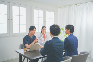 クリニックの会議室で打ち合わせをする若い医師とビジネスマン