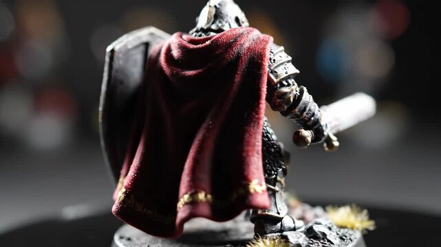 Miniature knight figure with shield and sword detailed armor and red cape.